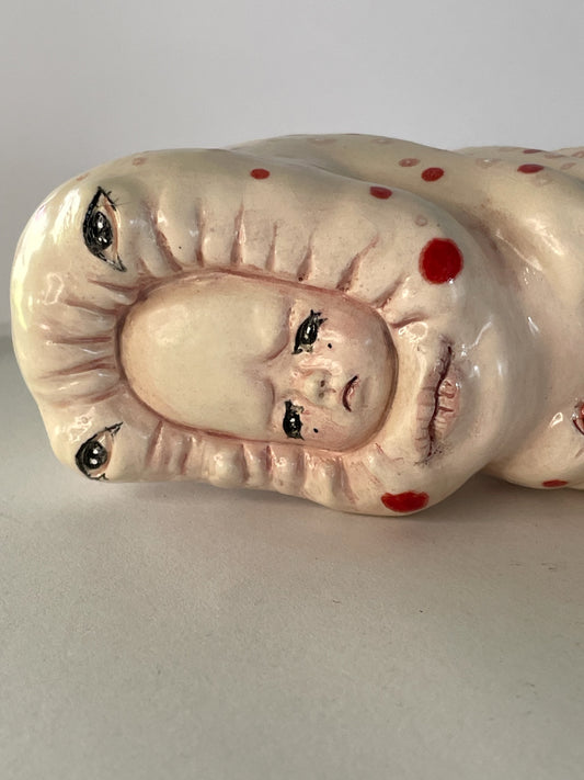 Escultura de bebé triste por su propia existencia en rojo