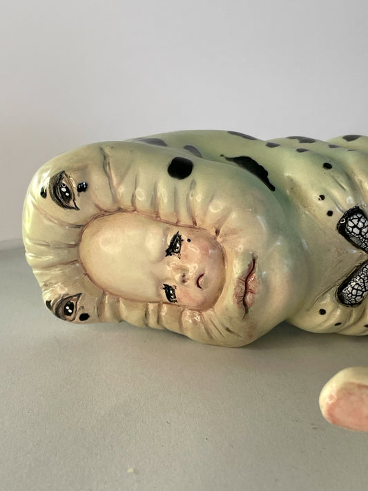 Escultura de bebé triste por su propia existencia en verde