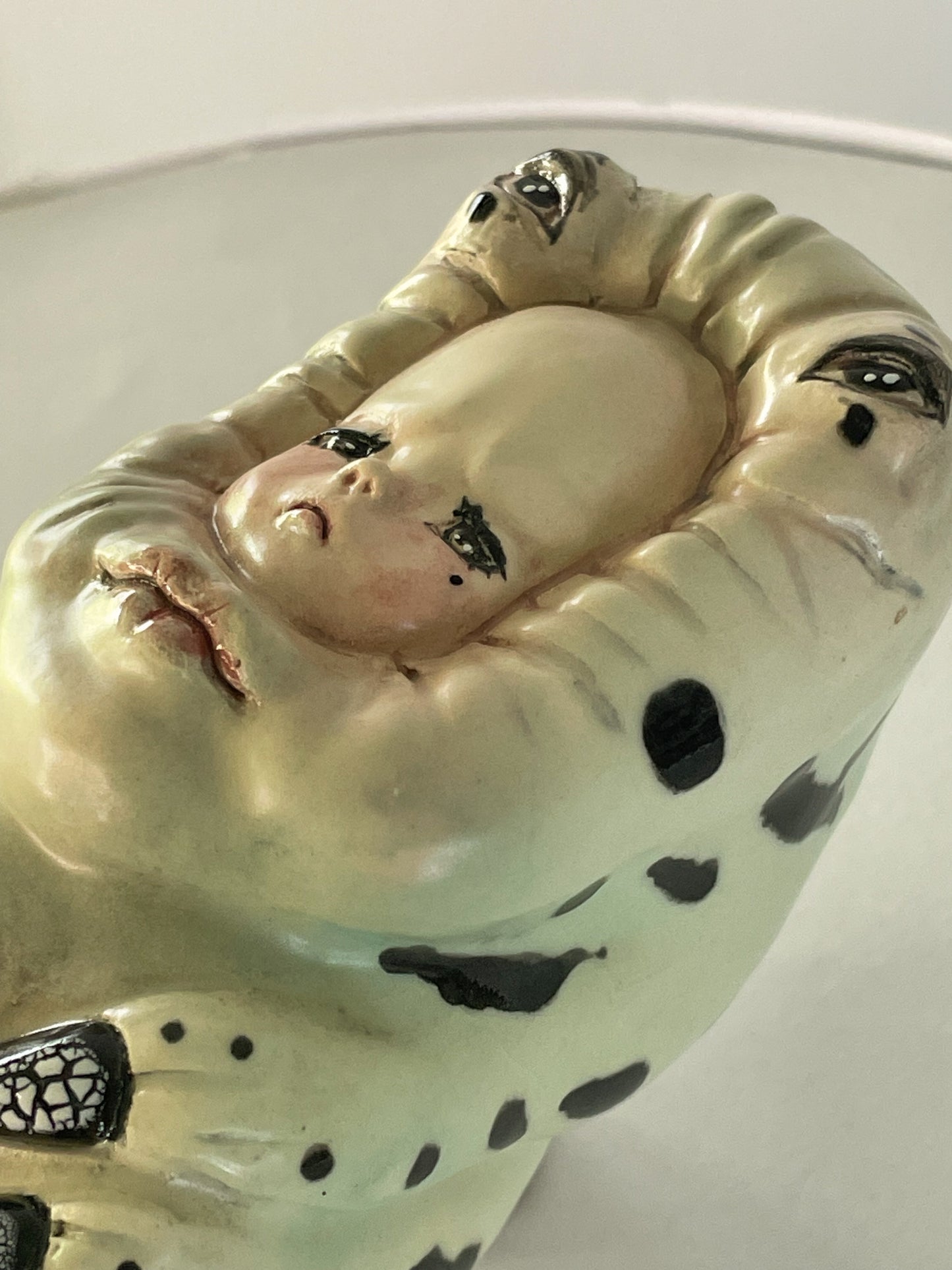Escultura de bebé triste por su propia existencia en verde
