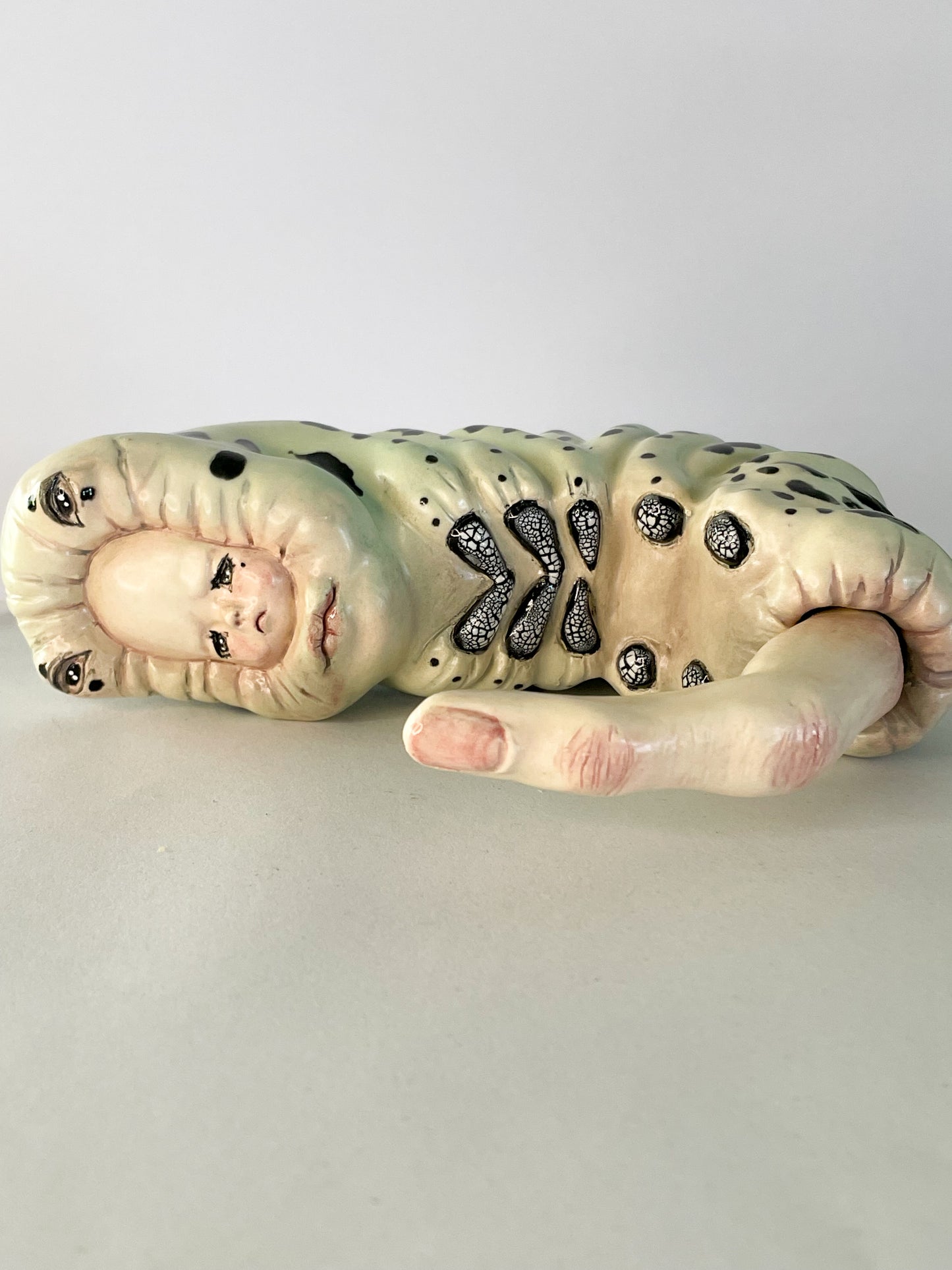 Escultura de bebé triste por su propia existencia en verde